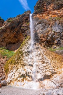 Majestic rinka waterfall flows down a rocky cliff face on a sunny summer day in logarska dolina