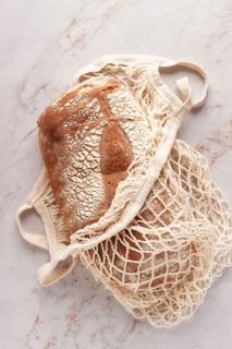 Freshly baked rye bread, ciabatta, in a mesh bag, on a marble light table, natural light