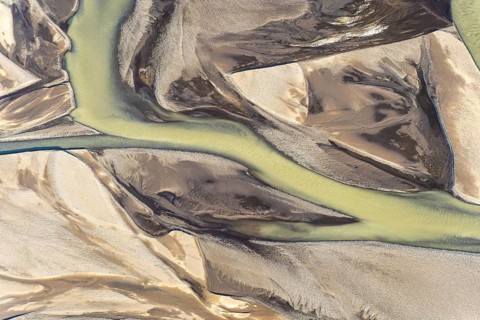 This stunning aerial photograph captures sinuous golden-tinted rivers flowing through a contrasting