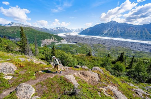 Young man on a hiking trail, view of impressive mountain landscape with Matanuska glacier and