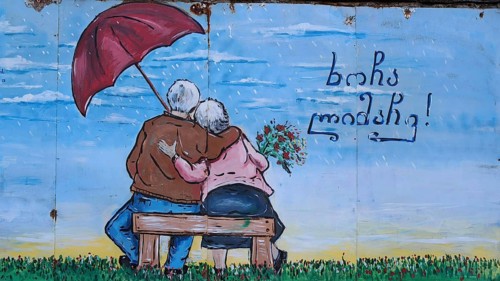 Mural of an elderly couple sitting on a bench with an umbrella, Georgia