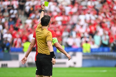 Referee shows yellow card during soccer match at the stadium