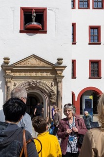 City guide with tourists in front of the Judith Lucretia portal with figurative carillon, Old Town
