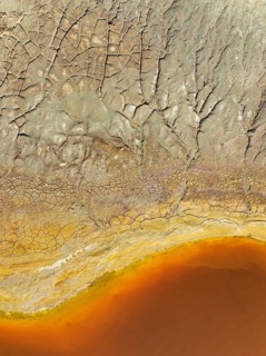 Cracked earth at the bank of the Rio Tinto (Red river) with its deep reddish hue due to oxidised