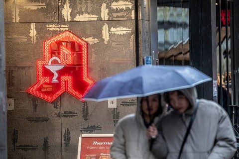 Symbolic picture of cold weather, rainy weather, person with umbrella, in front of a pharmacy,