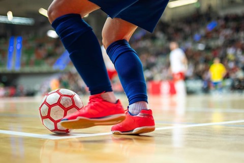 Detail of futsal ball and players legs