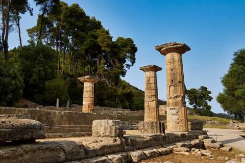 Temple of Hera, Heraion, Three preserved pillars in a historic site with a wooded background,