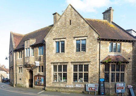 Historic local library building with sign and council noticeboard outside, Bruton, Somerset,