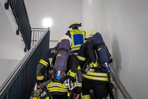 Firefighters climb up the stairwell, ready for their next mission, fire brigade exercise on blue