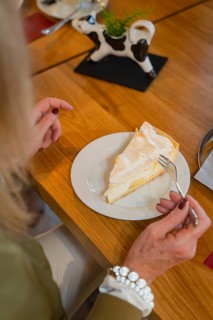 Woman enjoying a piece of lemon cake with meringue in a café, autumn creations, Cafe Kuh,