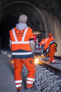 Construction worker in the tunnel during track work, surrounded by flying sparks, rail welding,