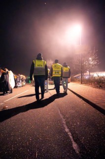 Group of people in reflective waistcoats walking on a foggy street at night, Fasching, Tiefenbronn,