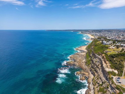 A breathtaking aerial view of the rugged coastal cliffs and expansive turquoise waters along the