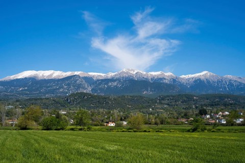 View of snowy mountains and a small village in the foreground under blue sky with clouds, landscape