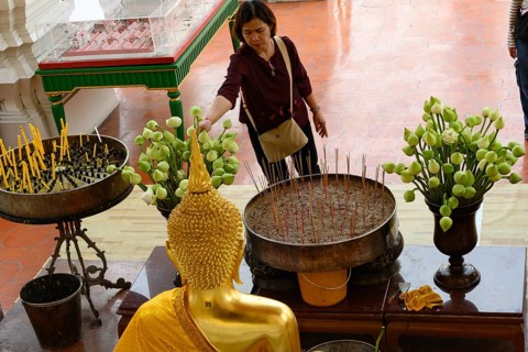 Bangkok, Thailand. February 20th 2025. A Thai visitor lights a candle and makes an offering of a