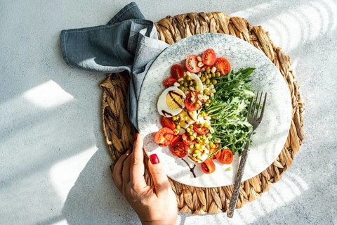 A nutritious keto lunch featuring boiled eggs, fresh rocket, cherry tomatoes, canned green peas,