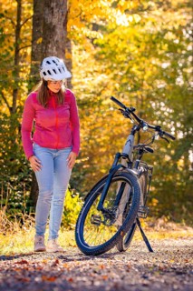 Woman looking at ebike in autumn forest, Black Forest, Gechingen, Germany