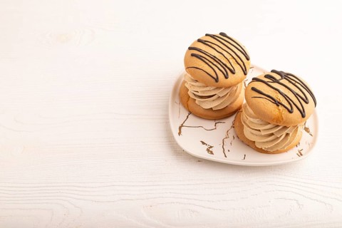 Caramel Cream Cakes on white wooden background, side view, copy space
