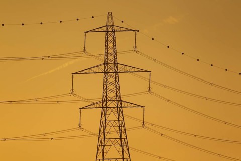 Electricity power pylon and cables silhouette at sunset, Lincolnshire, England, United Kingdom