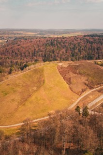 Aerial view of a hilly landscape with forest, fields and a hiking trail in autumn atmosphere, old