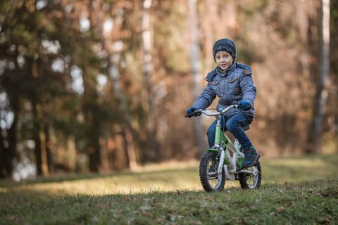 Six years old boy rides bicycle from the hill in the park