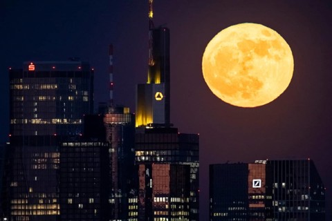 The full moon passes behind the Frankfurt banking skyline, Frankfurt am Main, Hesse, Germany