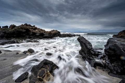 Waves blaze on the beach, rocky coast with volcanic stones, long exposure, Playa de la Pequeña,