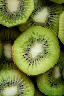 A close up of fresh kiwi slices showcasing vibrant green flesh with contrasting black seeds.