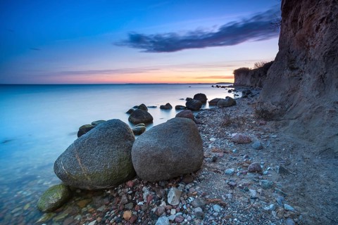 Rocky beach with large boulders on the cliffs on the Bay of Greifswald at dusk after sunset,