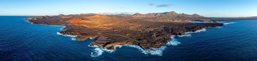 Coast with lava fields, volcanic landscape near Los Hervideros with red volcano Montaña Bermeja, in