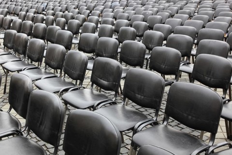 Chairs covered with gray plastic stand in rows in a function room, empty, vacant, seating