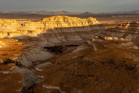Eroded sedimentary rock formations with horizontal stratification in evening light, gorges and