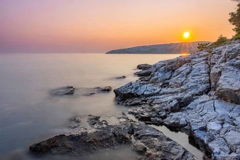 Sunset over crystal clear water on the beach of Ustrine Bay on the island of Cres, long exposure,