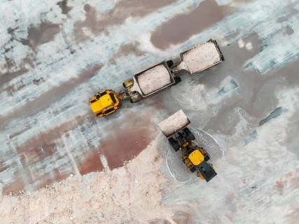 Excavator and lorry at a harvesting pan of the Walvis Bay Salt works. Aerial view. Drone shot.