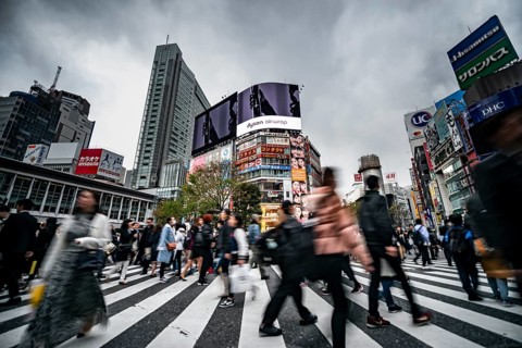 Crowd crossing zebra crossing on a large intersection, motion blur, back modern houses with