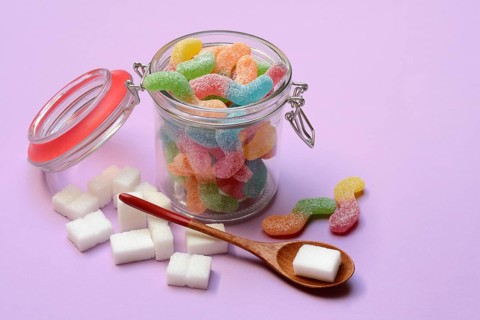 Lots of colorful jelly sweets in glass containers and sugar cubes, sugar consumption
