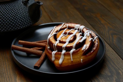 Cinnamon roll on plate and cinnamon sticks