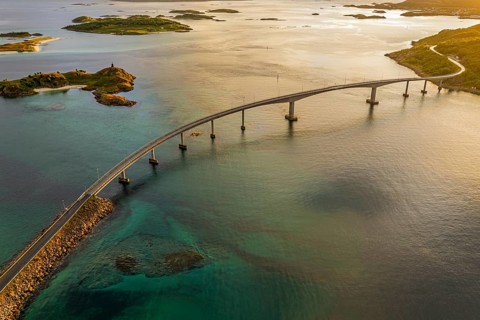 Sommaroy Bridge connecting Kvaloya Island to Sommaroy Island, warm light at sunset, aerial view,