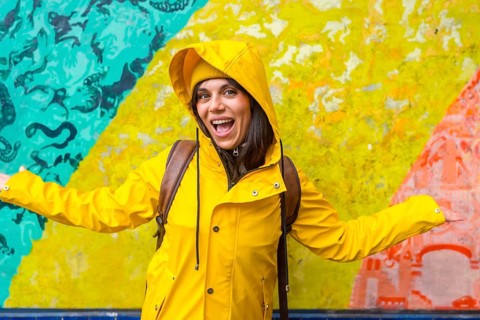 Young woman smiling with open arms, enjoying urban street art and vibrant colors while exploring