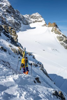 Mountaineer with skis at the fork Porta d'Es-cha, view of mountain peak Piz Kesch and glacier