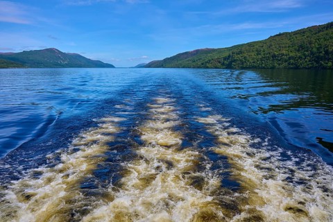 Wave movement on a river surrounded by rolling landscape and blue sky, Fort Augustus, Loch Ness,