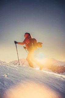 A woman's ski tour at sunrise on the Tegelberg in the Allgäu in the Ammergebirge, Bavaria, Germany