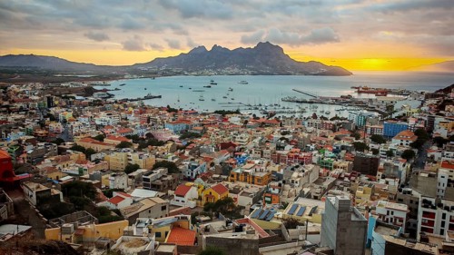 Panoramic view from above of coastal town of Mindelo at sunset with colorful buildings, harbor and