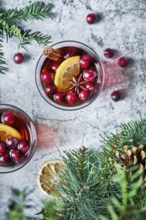 Top view of glasses with cranberries with lemon next to Christmas decoration