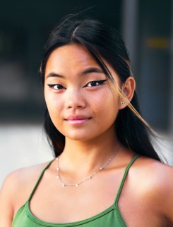 Close-up of a Chinese teenage girl with stylish makeup and confident expression. She wears a green