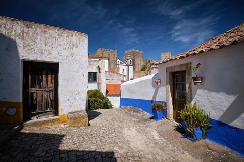 Narrow streets of Obidos, Portugal, white houses and castle walls under a bright sky