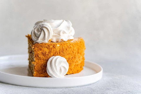 Homemade honey cake topped with smooth sour cream sauce and delightfully decorated with fluffy