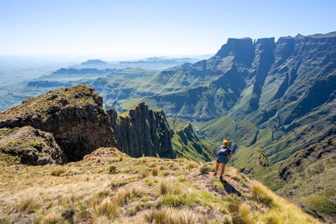 Young hiker looking at the impressive mountains and cliffs of the Drakensberg Mountains, hiking