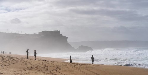 Tourists watch the waves of the Atlantic on the rocky plateau of Sito, also known as Forte São