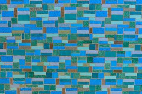 A detailed image of a mosaic wall consisting of blue and green tiles in geometric patterns,